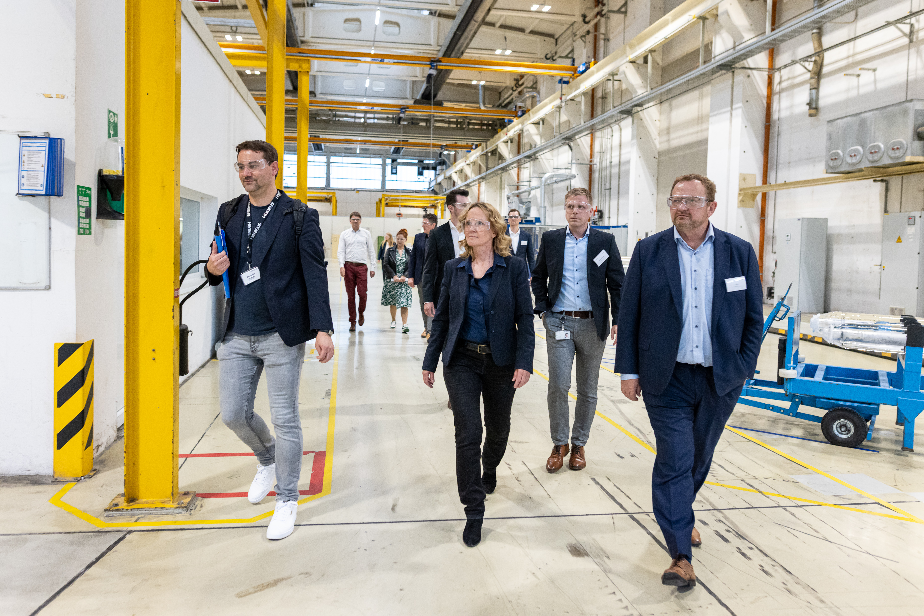 Minister, CEO of Heraeus Comvance and entourage walk through production hall.