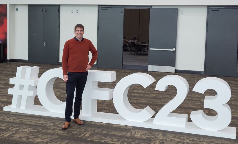 Representative of Heraeus Comvance in front of the huge “#OFC2023” logo