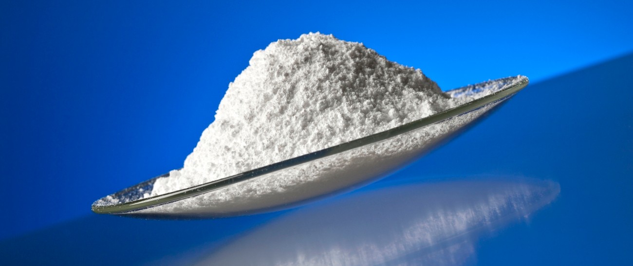 white powder in glass bowl in front of a blue background 