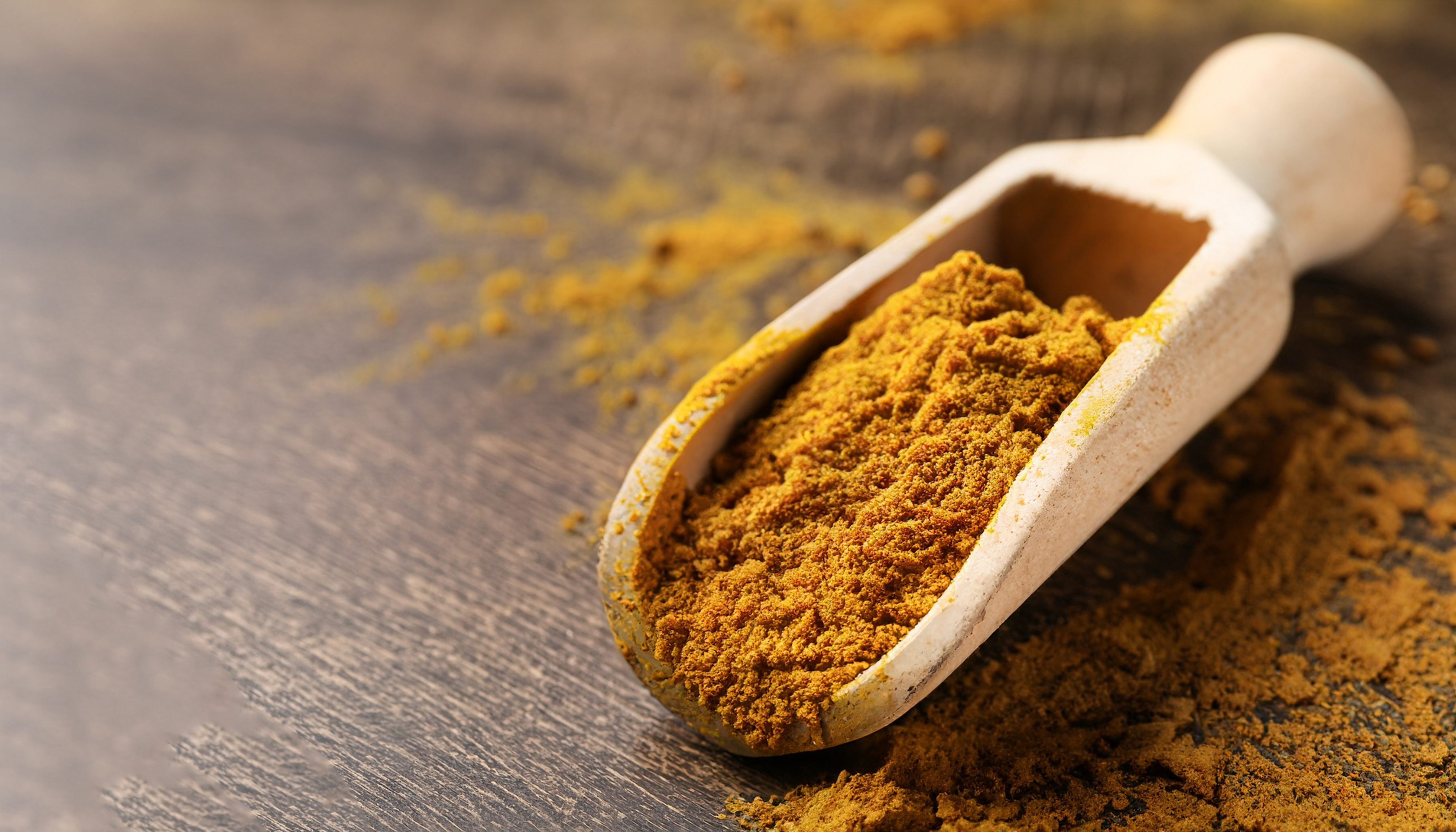 spice shovel filled with curry powder on a wooden base 