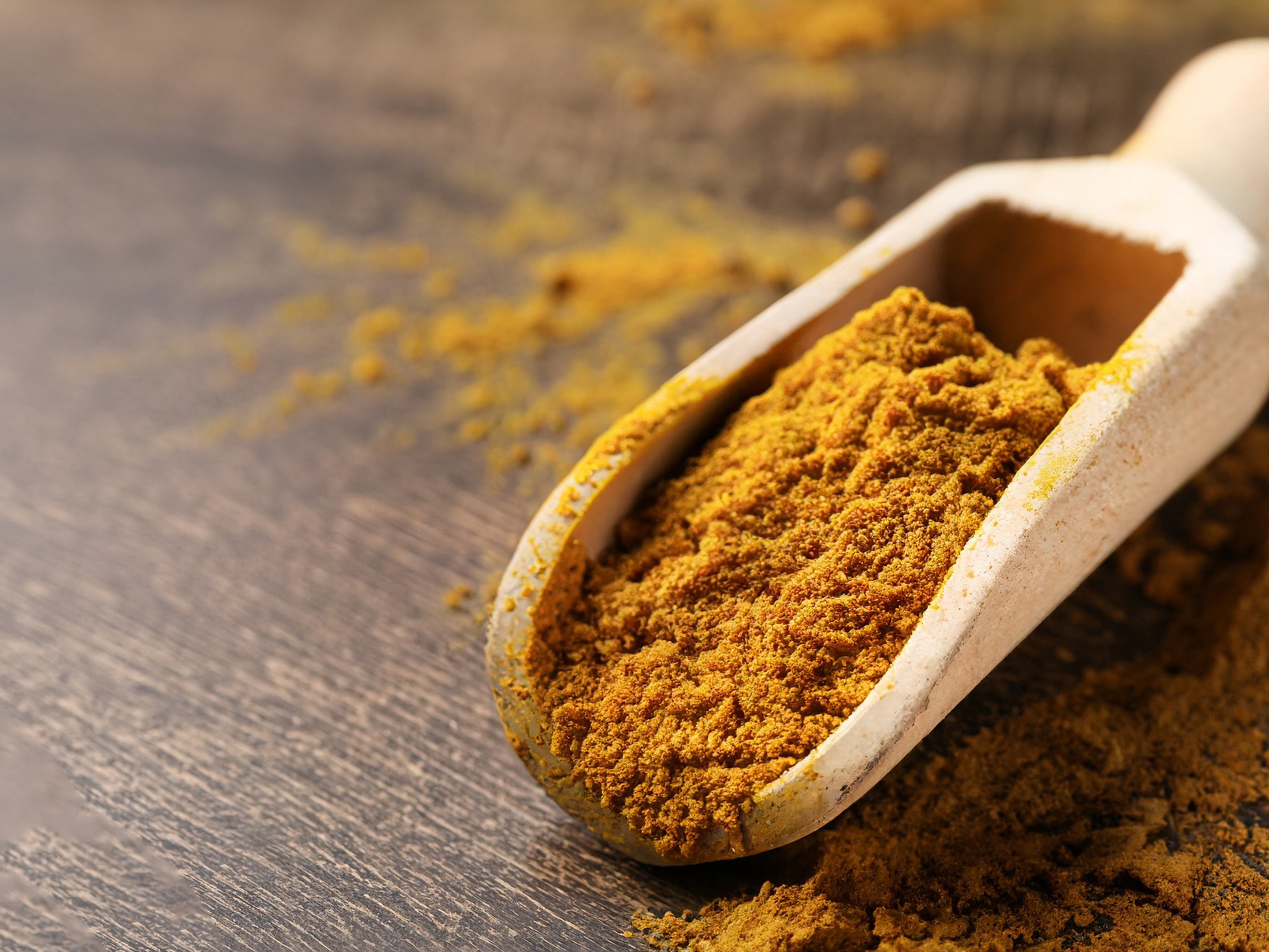 spice shovel filled with curry powder on a wooden base 