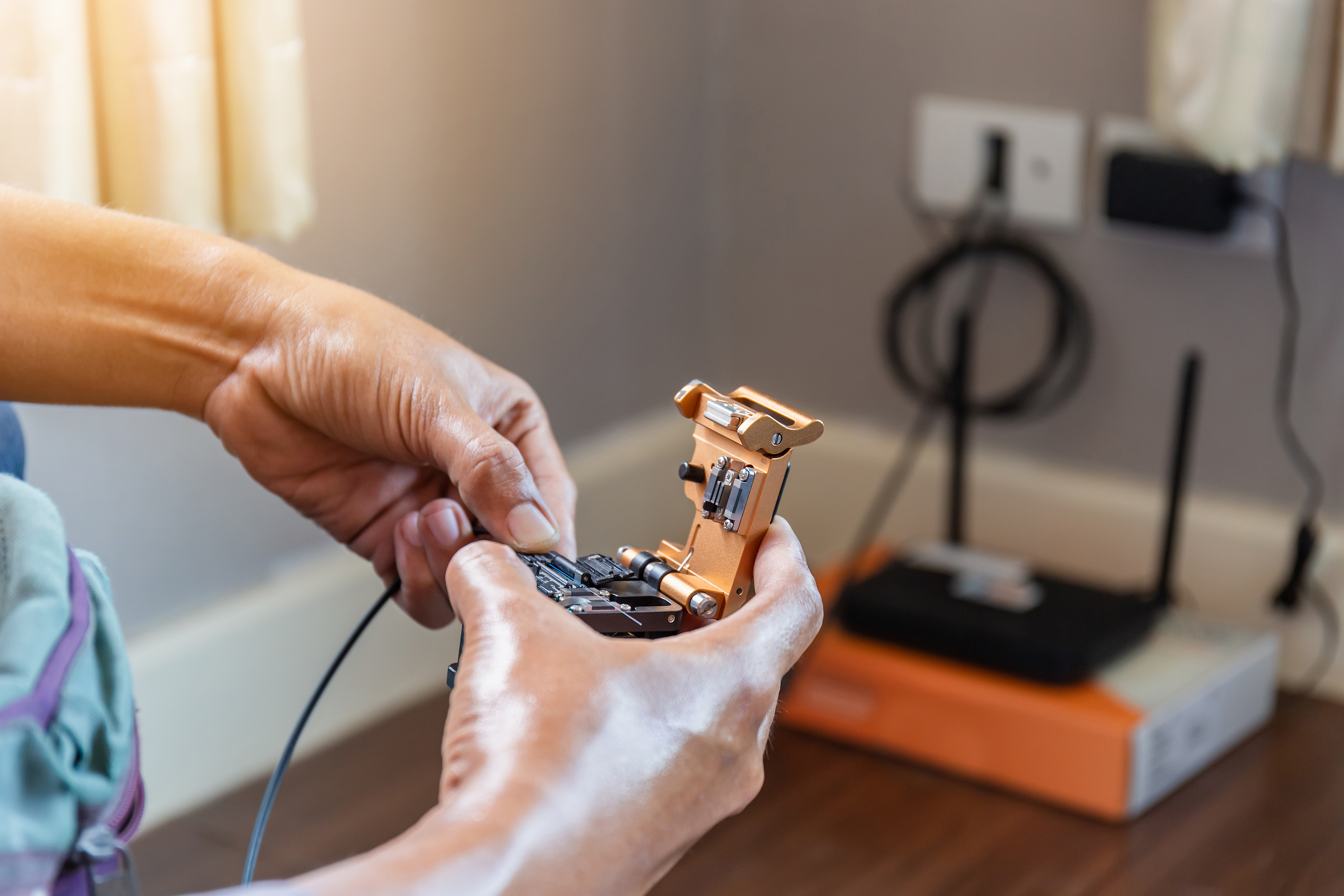 Selective focus of internet technicians man are cutting fiber optic cables with cutting tool and prepare for splicing, Home IT network concept