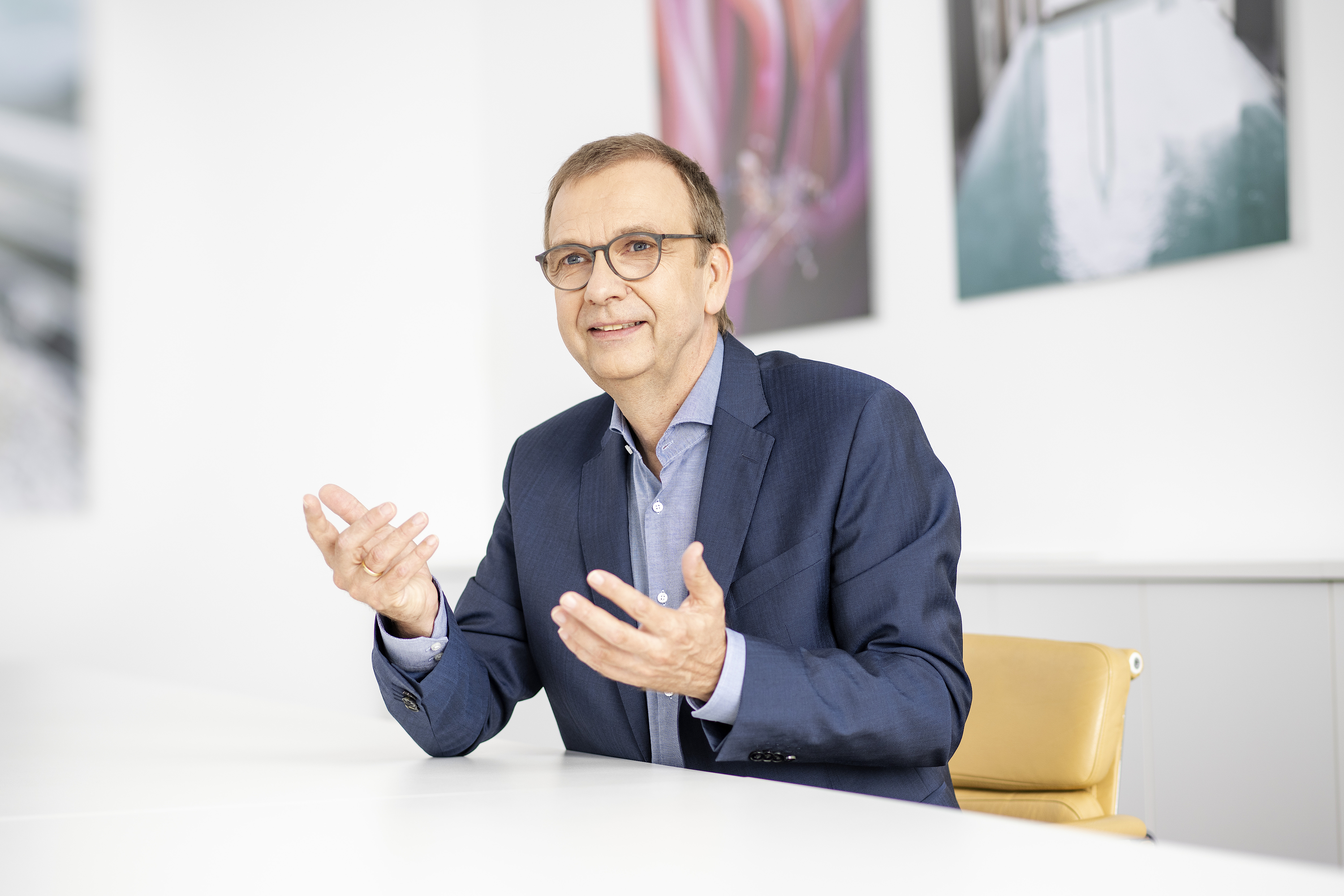 A man in a suit is sitting at a table and explaining